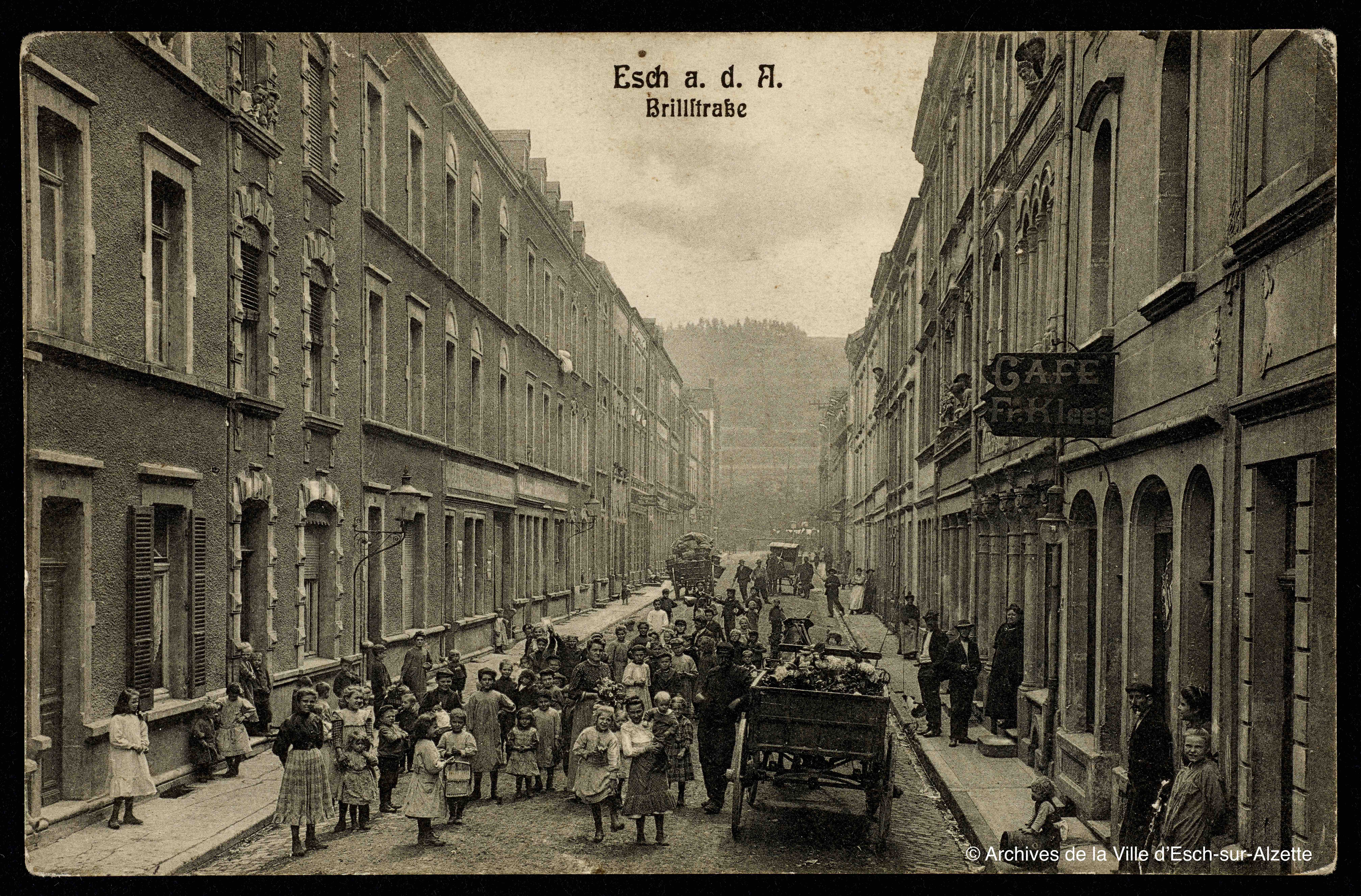 old sepia toned photograph of a crowded Brill Street filled with people, a cart, and tall buildings on either side