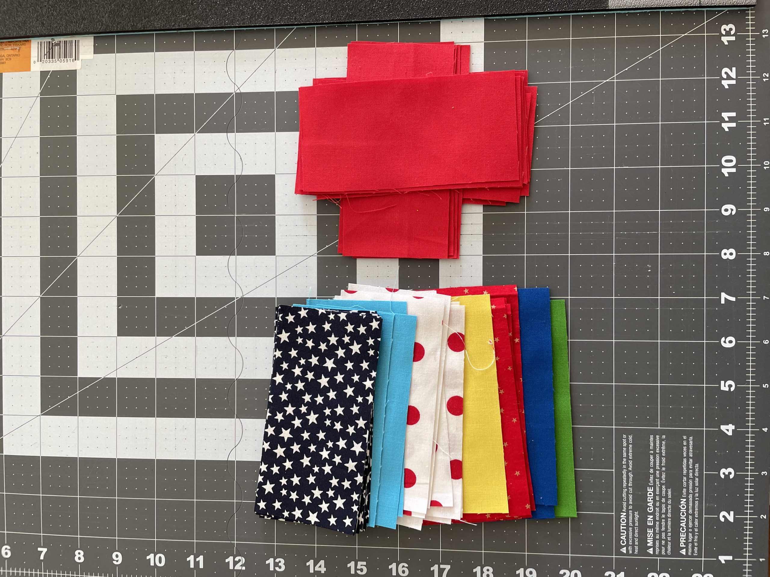 Assorted color fabric strips on a sewing table with grid and ruler.