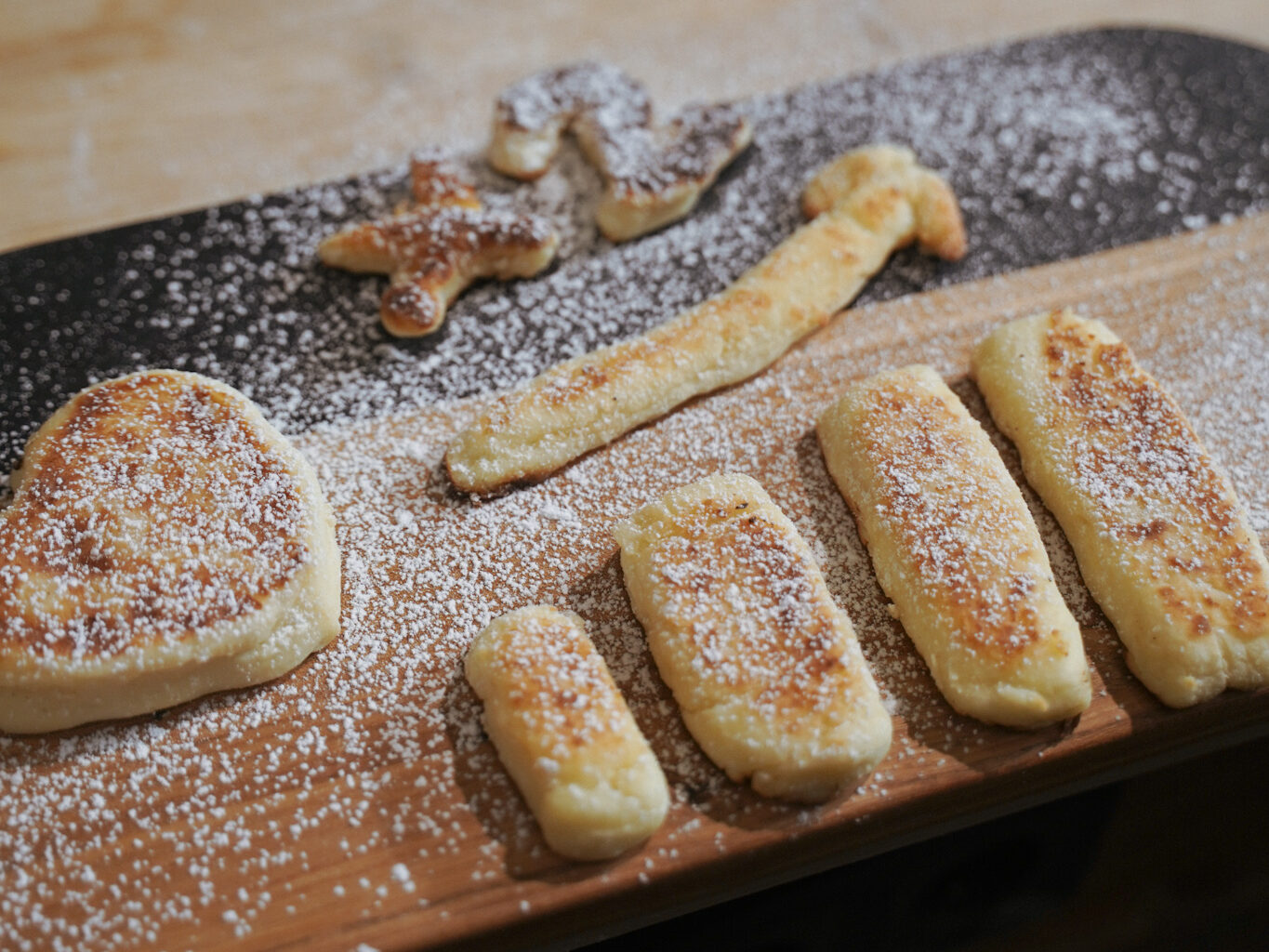 A cutting board of pancakes in the shape of data visualization charts, sprinkled with powdered sugar.